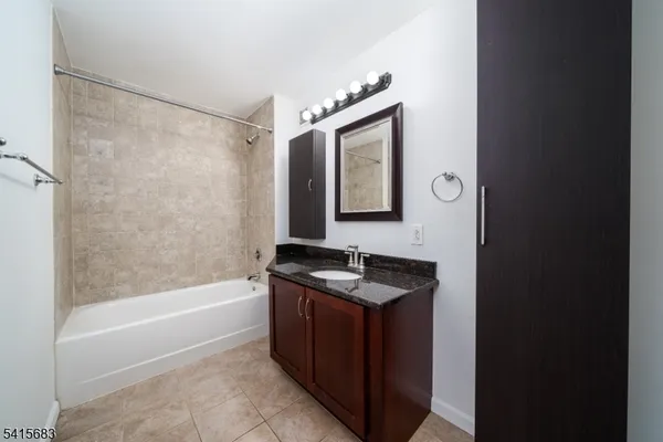 a bathroom with a granite countertop sink a mirror a bathtub and shower