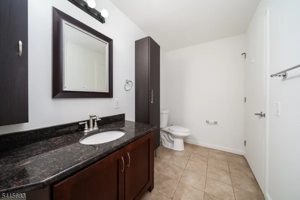 a bathroom with a granite countertop sink toilet and mirror