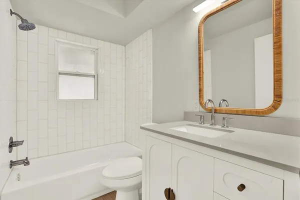 a bathroom with a granite countertop sink a toilet and shower