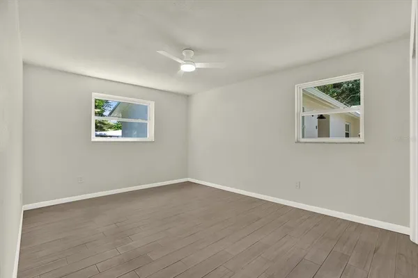 a view of an empty room with wooden floor and a window
