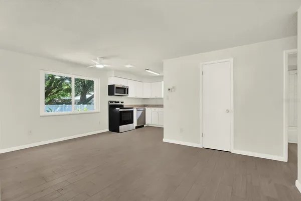 an empty room with windows and kitchen view