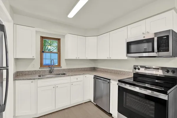 a kitchen with stainless steel appliances granite countertop white cabinets a sink and a stove