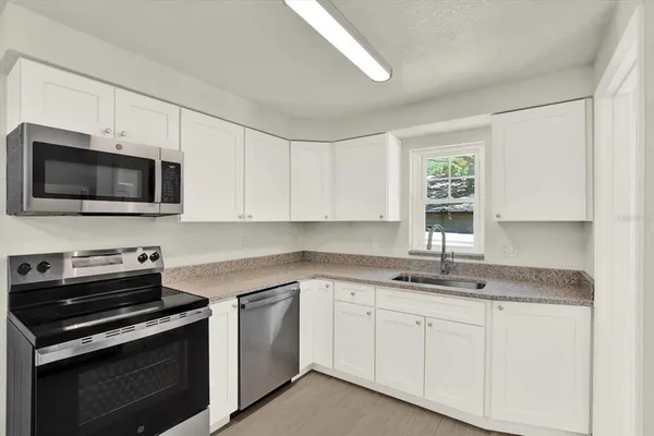 a kitchen with stainless steel appliances granite countertop white cabinets a sink and a stove