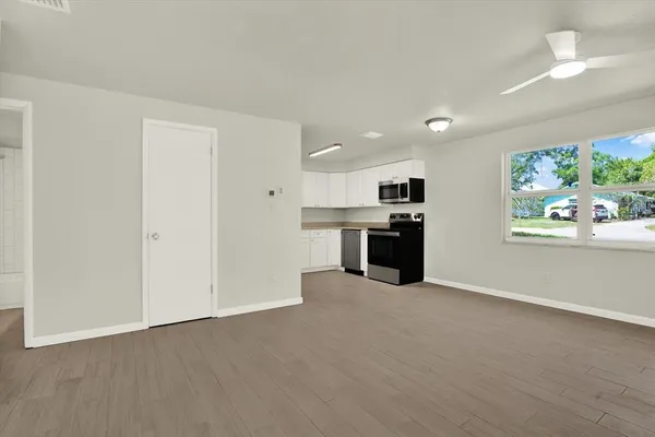 an empty room with windows and kitchen view