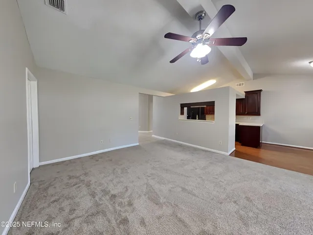 a view of an empty room with a ceiling fan and window
