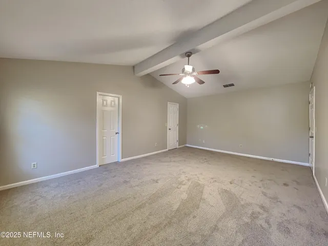 a view of an empty room with a chandelier fan