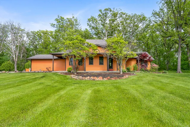 a backyard of a house with table and chairs plants and large tree