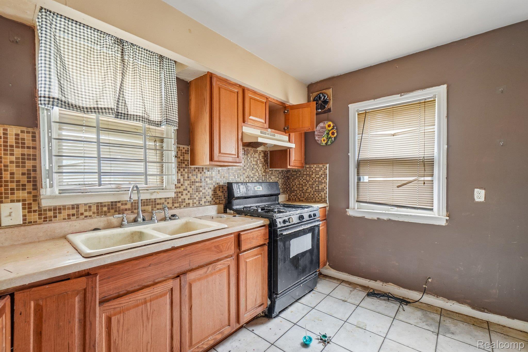 Kitchen featuring black gas stove, light countertops, light tile patterned flooring, and healthy amount of natural light