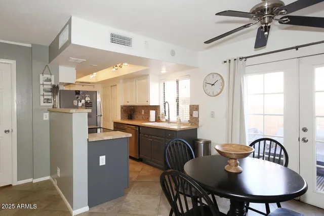 a kitchen with stainless steel appliances granite countertop a dining table chairs refrigerator and sink