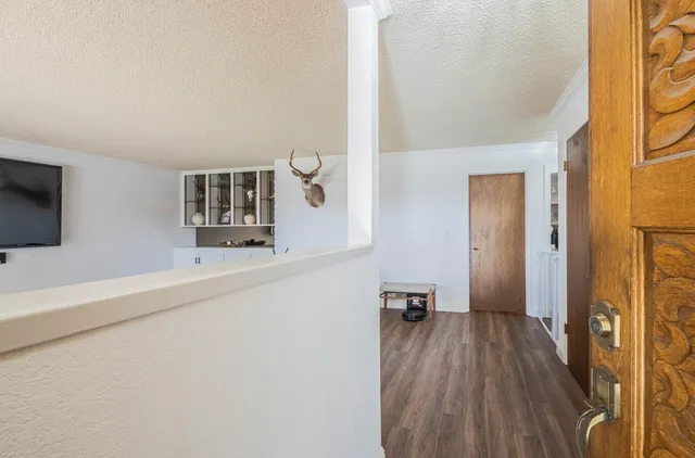 a view of a hallway with wooden floor and furniture
