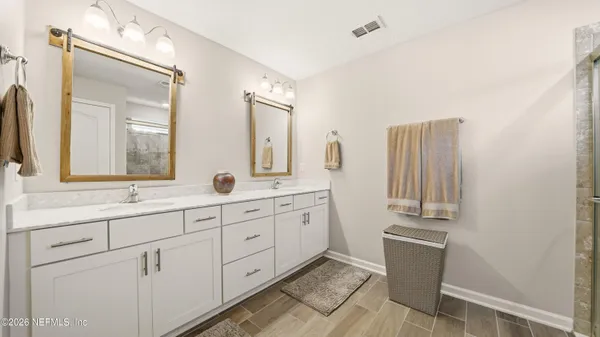 a spacious bathroom with double vanity a mirror a bathtub and a shower