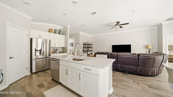 a living room with stainless steel appliances furniture and a flat screen tv