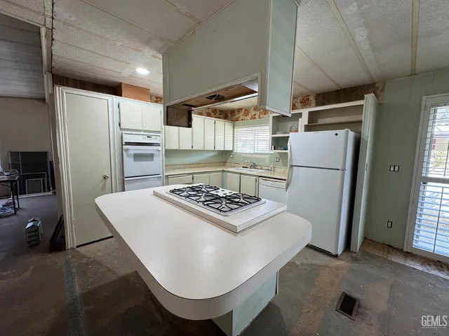 a kitchen with a refrigerator a stove a sink dishwasher and white cabinets with wooden floor