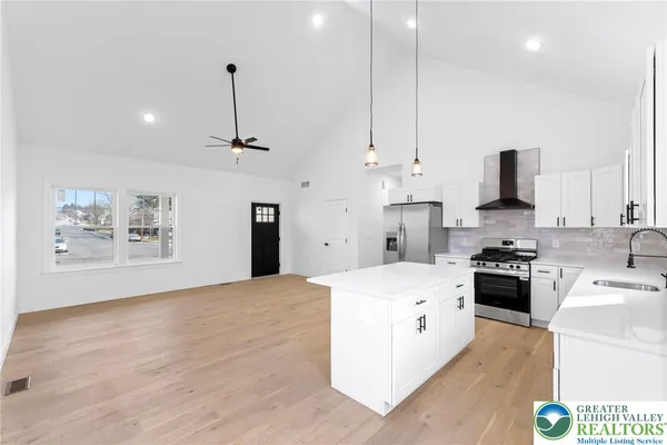 a large white kitchen with a stove a sink dishwasher and a refrigerator with wooden floor