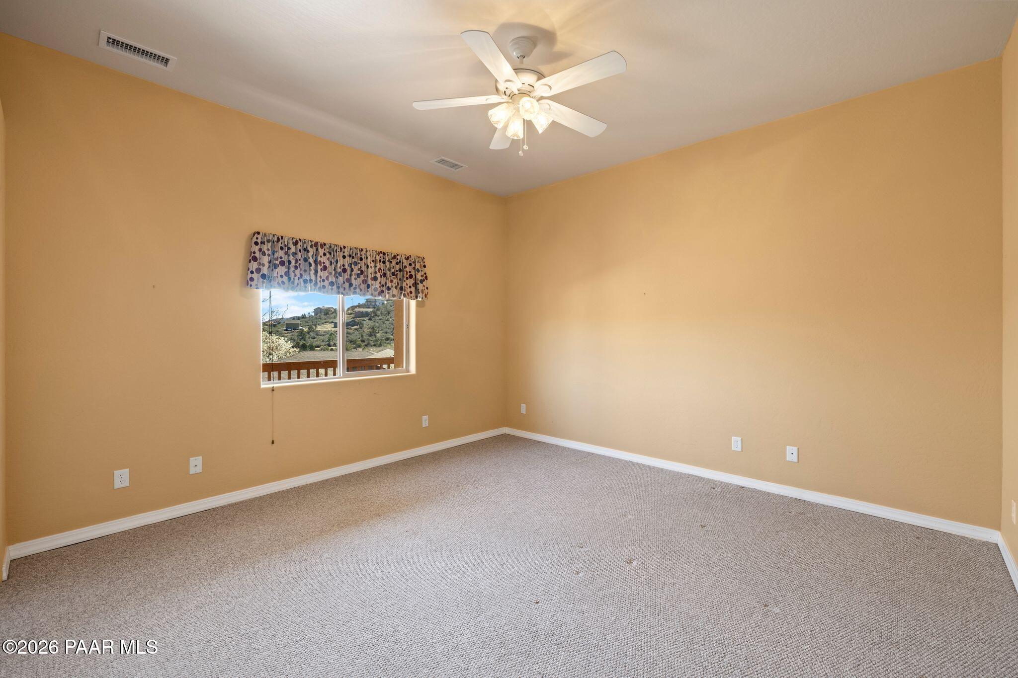 4677 Sharp Shooter Way Prescott, AZ 86301 - Photo 49 of 64 an empty room with a chandelier fan and windows