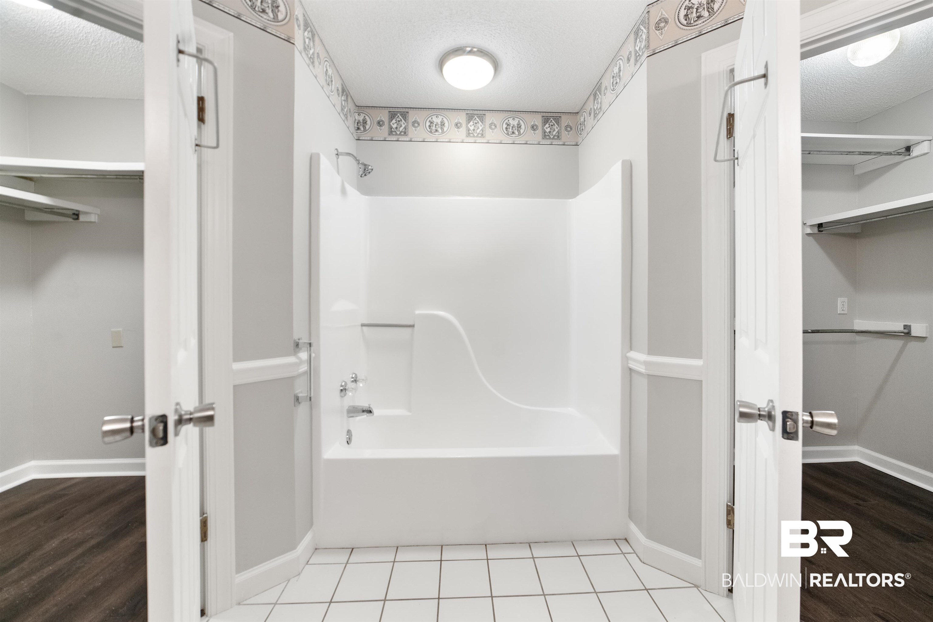 11833 Old Moffat Road Wilmer, AL 36587 - Photo 9 of 23 Full bathroom featuring bathtub / shower combination, a walk in closet, a textured ceiling, and wood finished floors