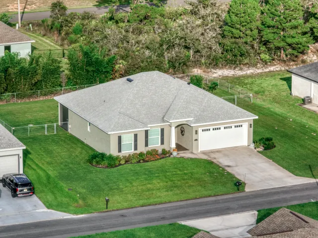 a aerial view of a house next to a big yard and large trees