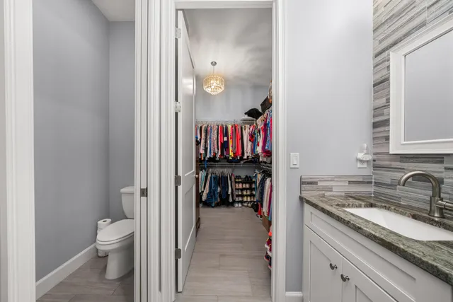 a en suite bathroom with a granite countertop sink a toilet and a mirror