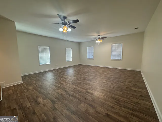 an empty room with windows and fan