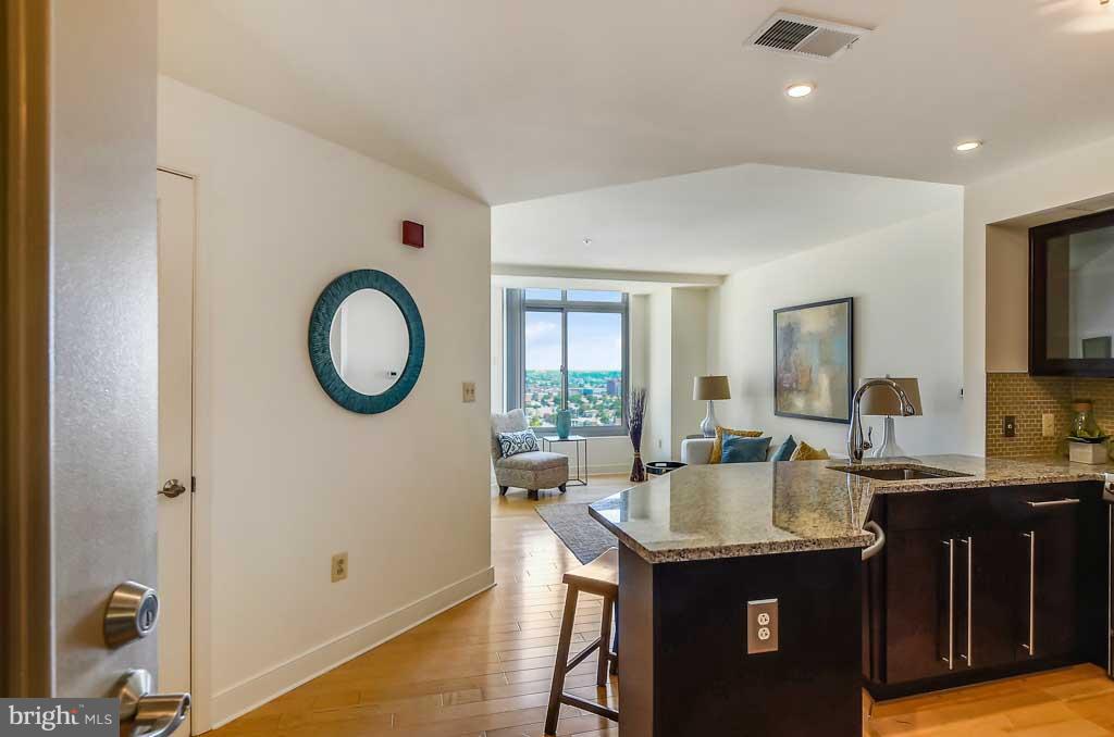 675 President Street, Unit 2607 Baltimore, MD 21202 - Photo 5 of 18 a dining hall with granite countertop a sink dishwasher a dining table and chairs with wooden floor