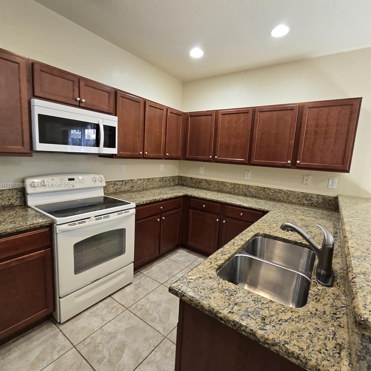 9051 Southwest 227th Street, Unit 3 Cutler Bay, FL 33190 - Photo 14 of 33 a kitchen with granite countertop a sink and a stove top oven