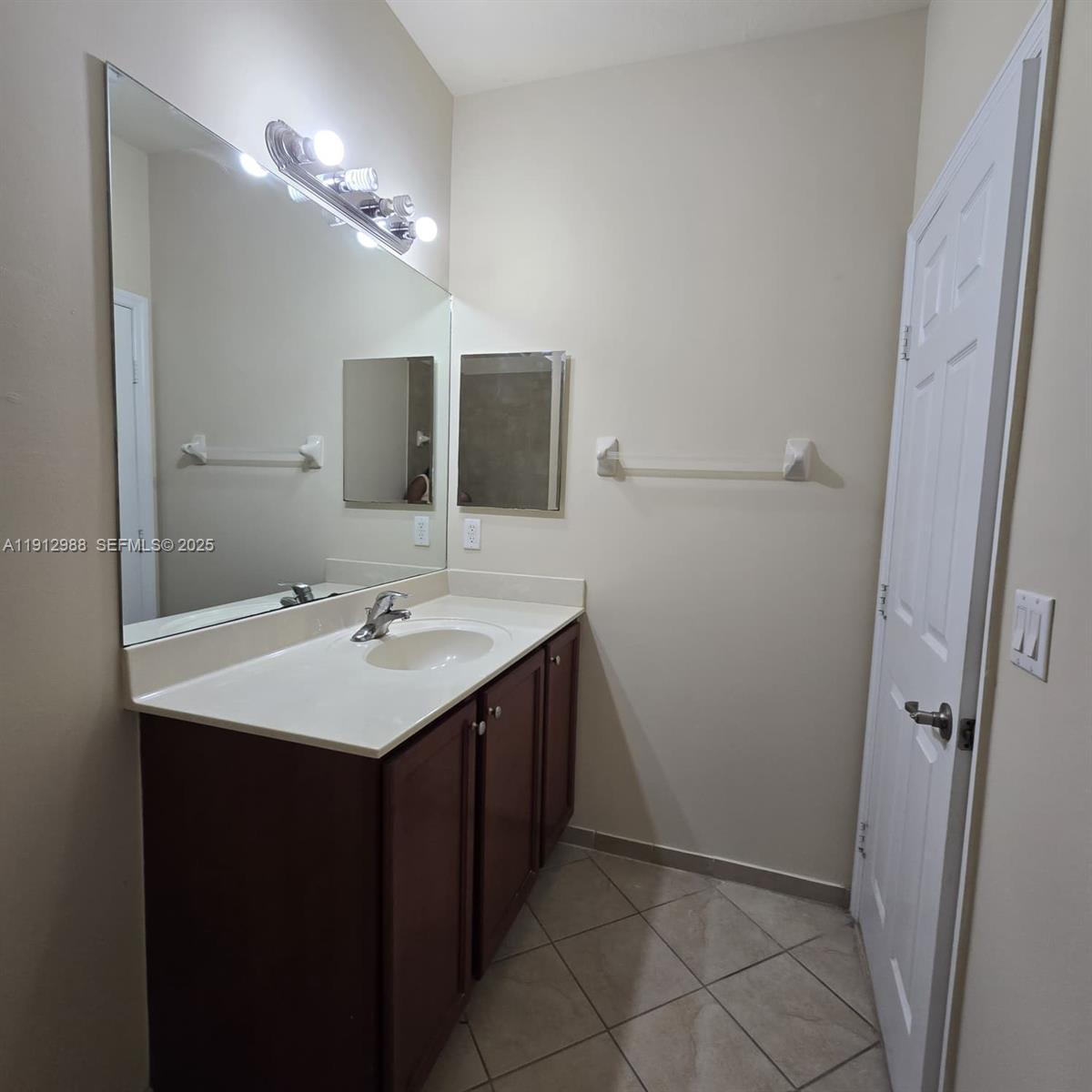 9051 Southwest 227th Street, Unit 3 Cutler Bay, FL 33190 - Photo 21 of 33 a bathroom with a sink a mirror and vanity