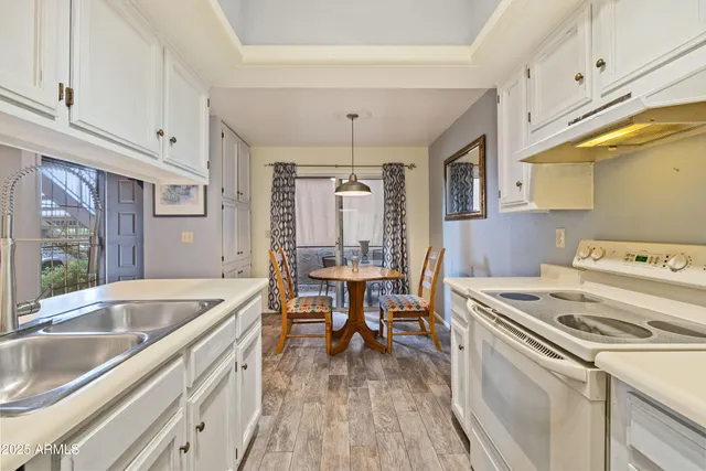 a kitchen that has a sink a stove and wooden floors