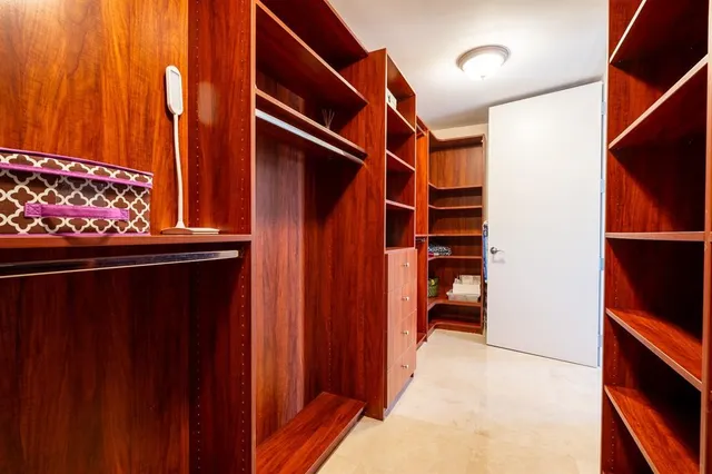 a view of walk in closet with clothes and shoes