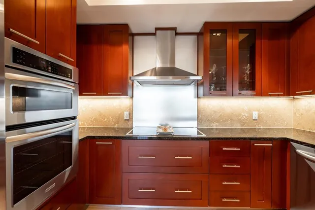 a kitchen with granite countertop a sink cabinets and stainless steel appliances