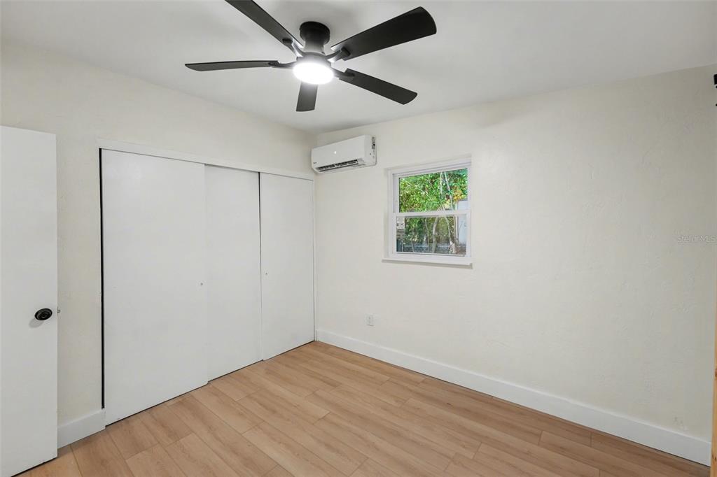 9482 Crestview Street Seminole, FL 33772 - Photo 18 of 35 an empty room with wooden floor ceiling fan and windows