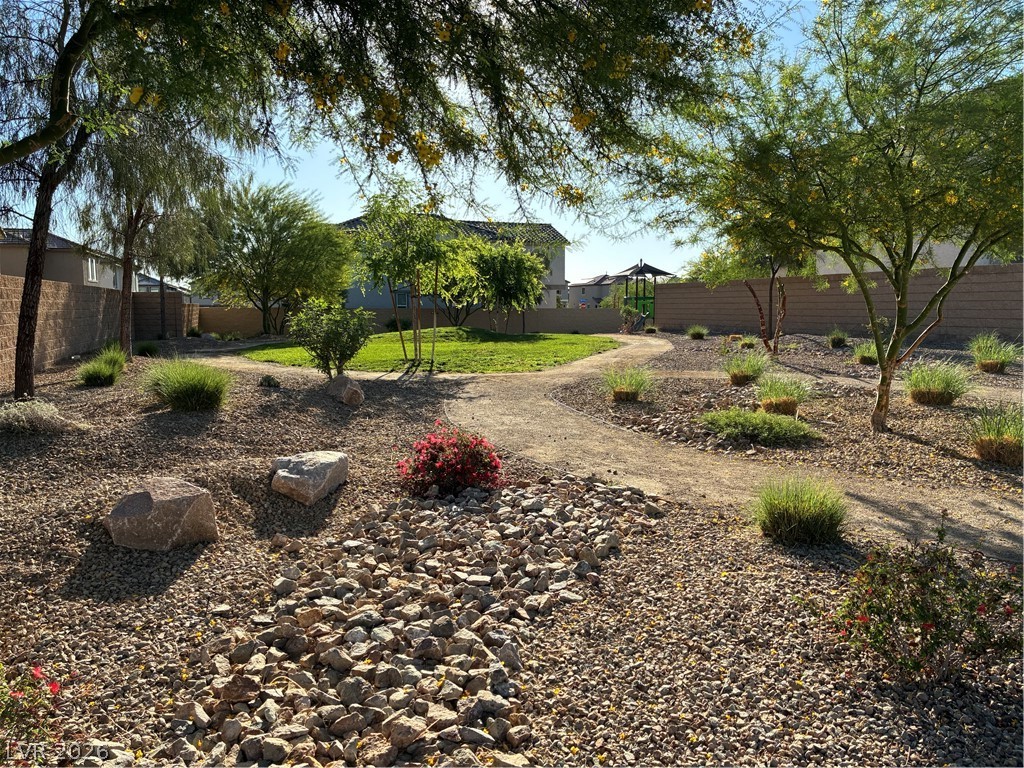 1921 Miller Ridge Avenue North Las Vegas, NV 89031 - Photo 26 of 26 This tranquil yard features a meandering pathway, lush greenery, and desert-inspired landscaping, creating a serene outdoor escape.