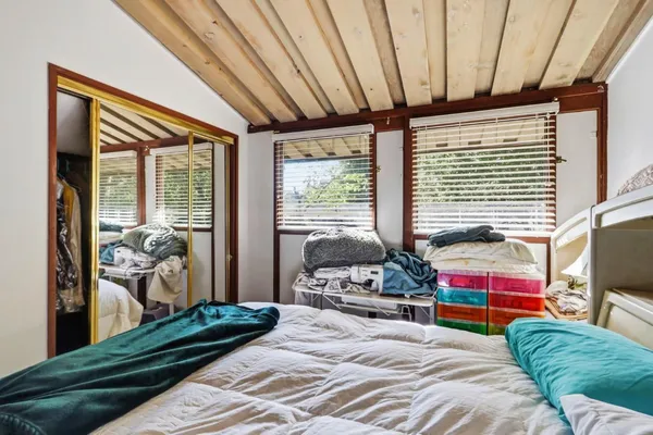 a bedroom with a bed wooden floor and flat screen tv
