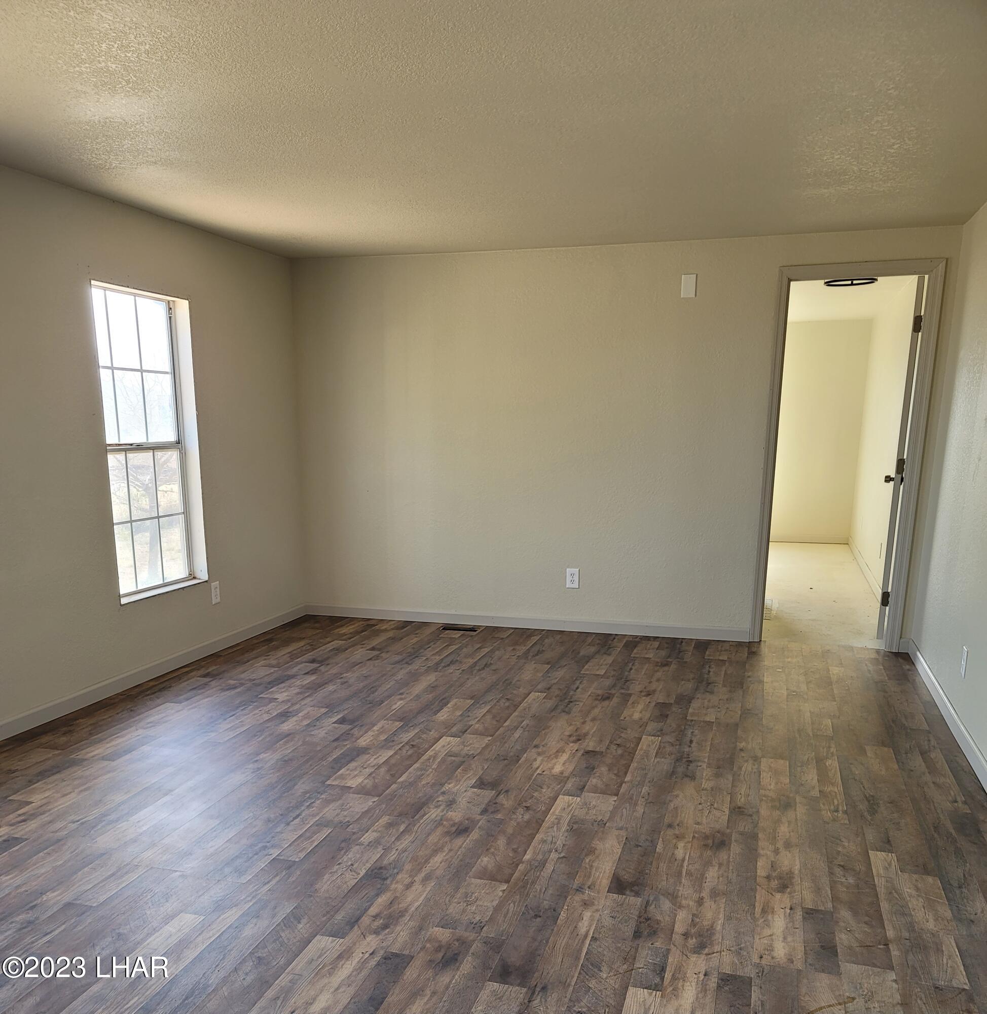 4944 Elgin Road Golden Valley, AZ 86413 - Photo 4 of 14 an empty room with wooden floor and windows