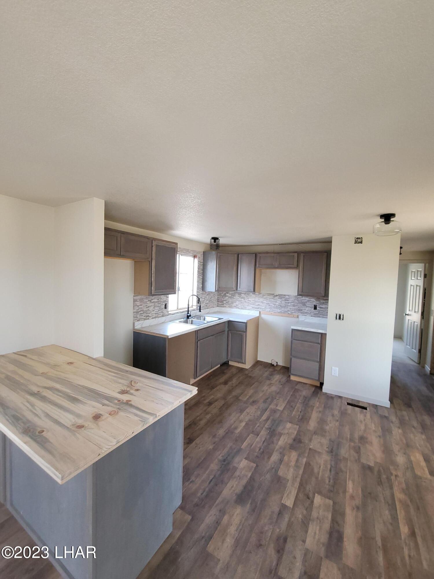 4944 Elgin Road Golden Valley, AZ 86413 - Photo 7 of 14 a open kitchen with a sink dishwasher stove and white cabinets with wooden floor