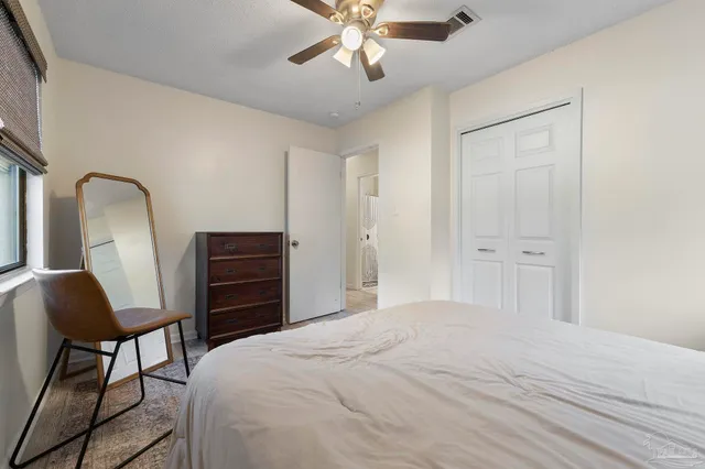 a bedroom with a bed and a chair with the wooden floor