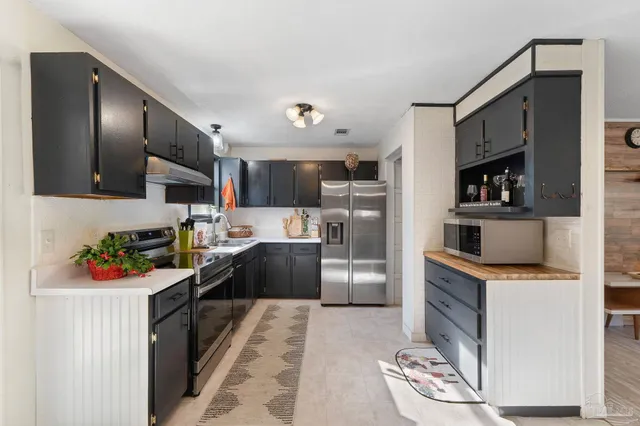 a kitchen with stainless steel appliances kitchen island granite countertop a refrigerator stove top oven and sink