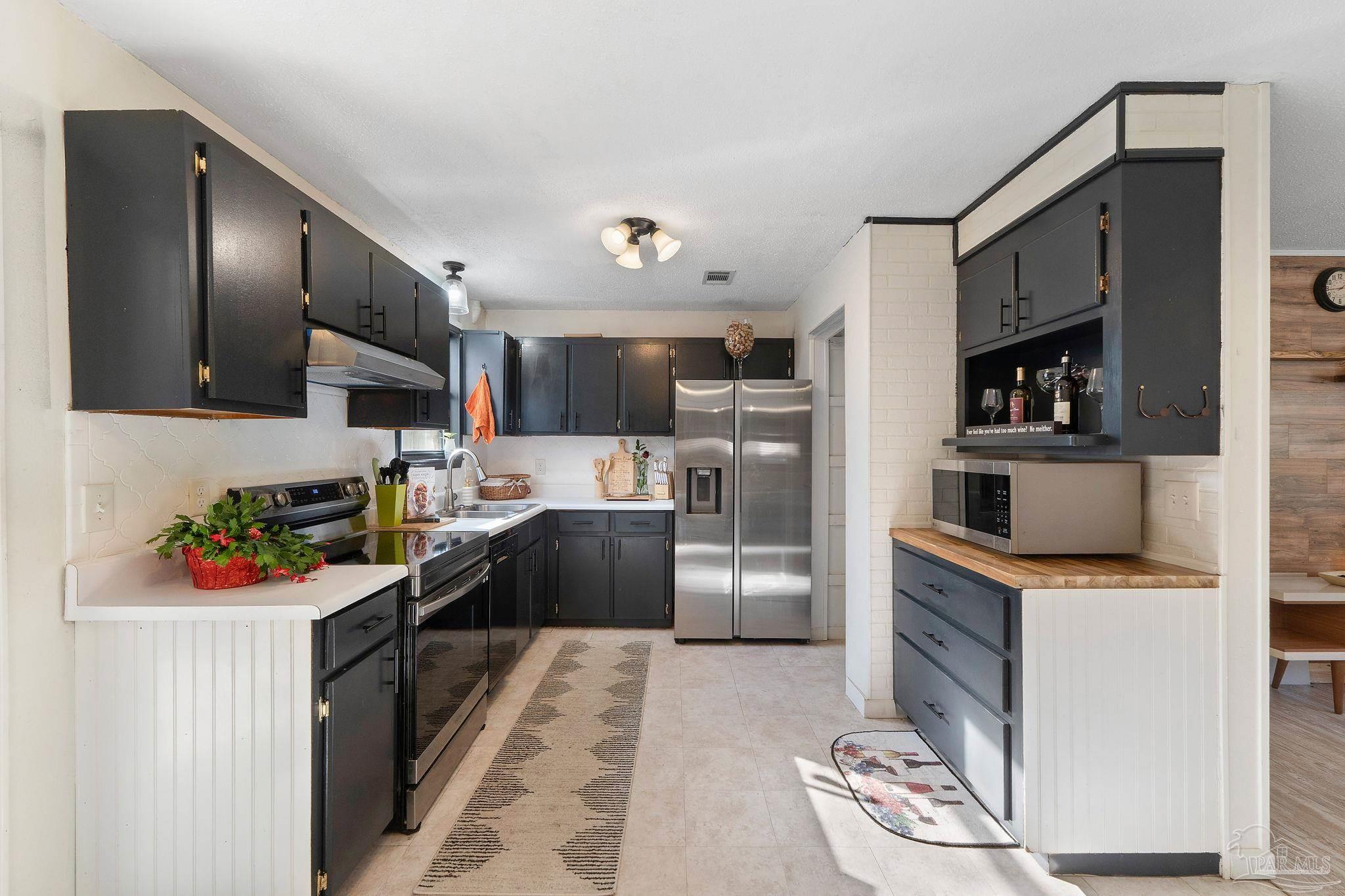 465 Ronda Street Pensacola, FL 32534 - Photo 9 of 48 a kitchen with stainless steel appliances kitchen island granite countertop a refrigerator stove top oven and sink