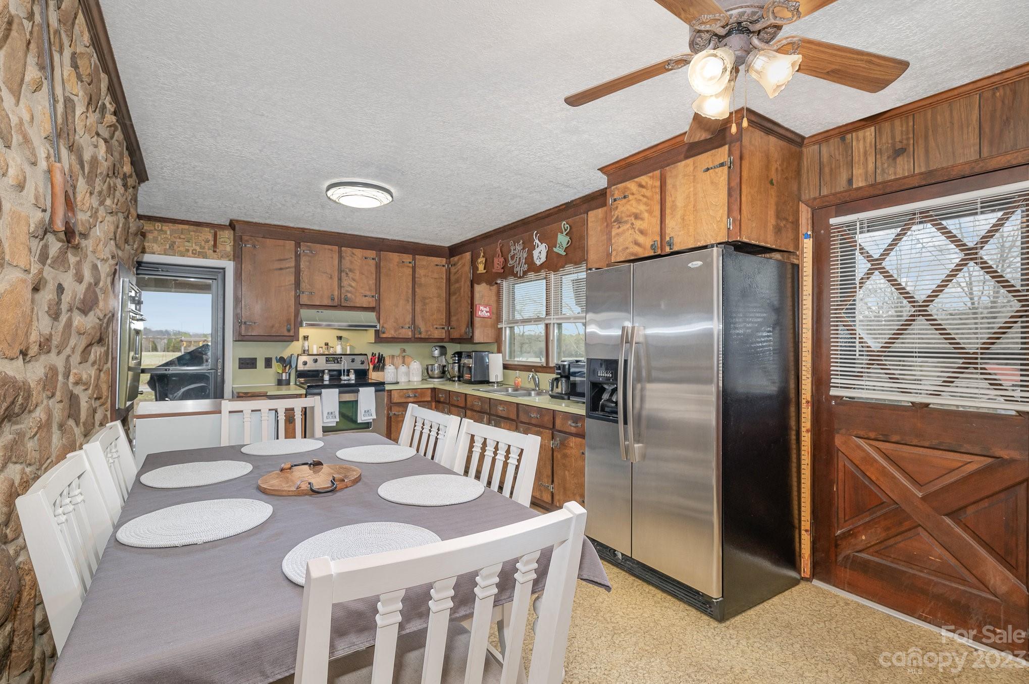 835 Parks Road Woodleaf, NC 27054 - Photo 8 of 28 a kitchen with stainless steel appliances granite countertop a refrigerator a stove a sink a dining table and chairs with wooden floor