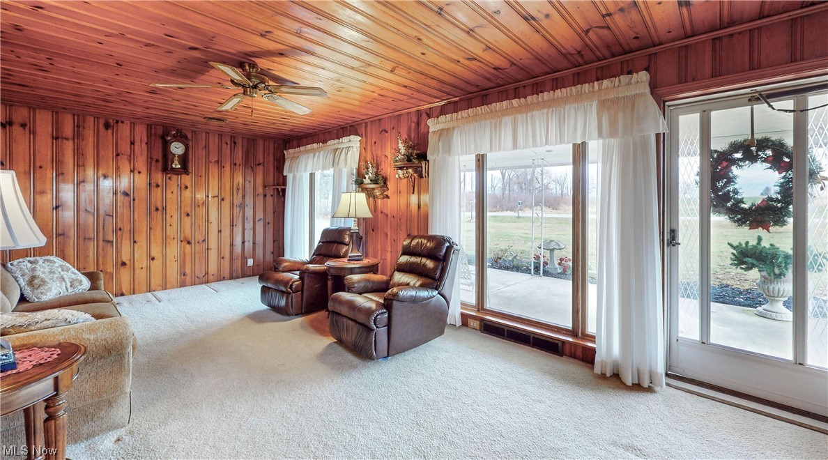 466 Pine Lake Road Sebring, OH 44672 - Photo 17 of 30 Carpeted living room with wooden walls, wood ceiling, and ceiling fan