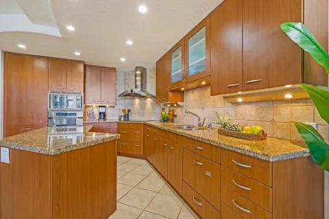a kitchen with kitchen island granite countertop wooden cabinets and a sink