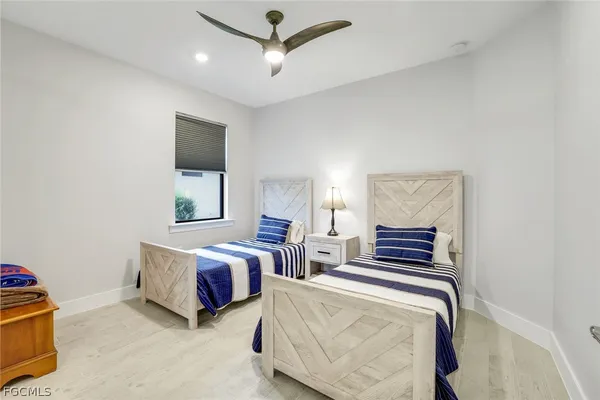 a bedroom with two beds and ceiling fan