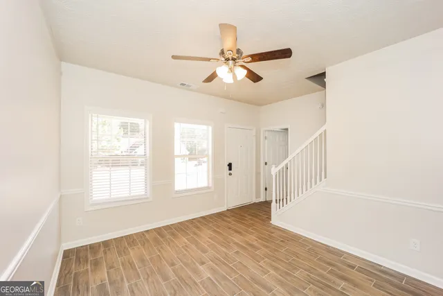 a view of an empty room with wooden floor and a window