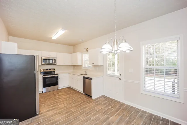 a kitchen with cabinets wooden floor and stainless steel appliances