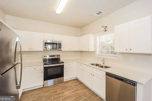 a kitchen with stainless steel appliances a sink cabinets and a window