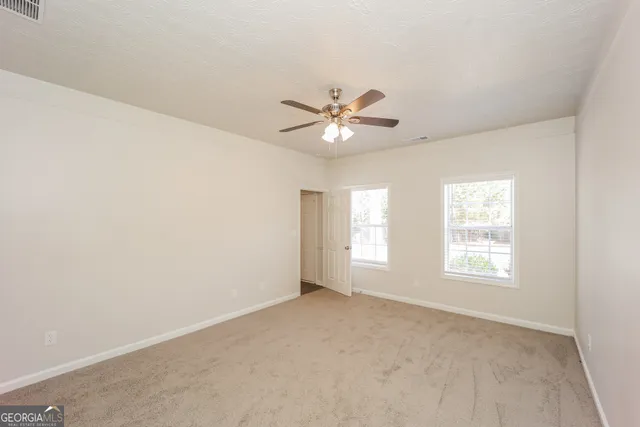 an empty room with windows and fan