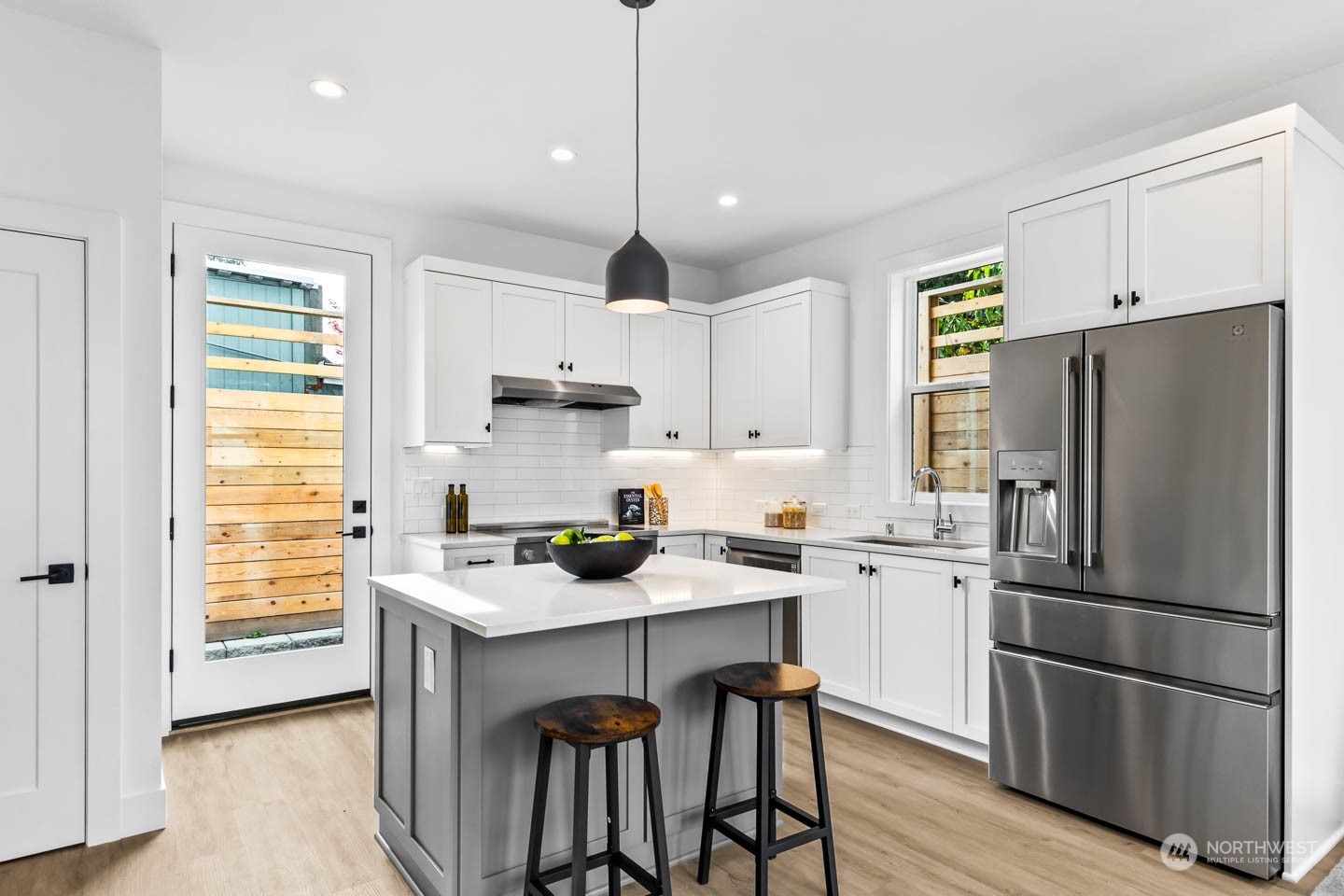 533 North 71st Street, Unit B Seattle, WA 98103 - Photo 3 of 23 a kitchen with stainless steel appliances granite countertop a refrigerator a sink dishwasher a stove and white cabinets with wooden floor