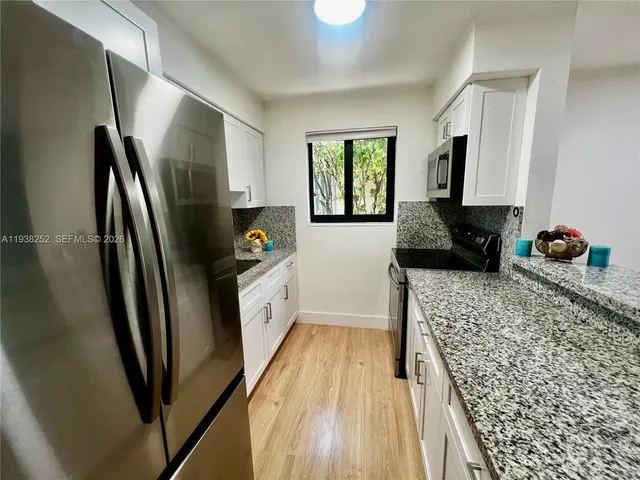 a kitchen with stainless steel appliances granite countertop a refrigerator and a sink