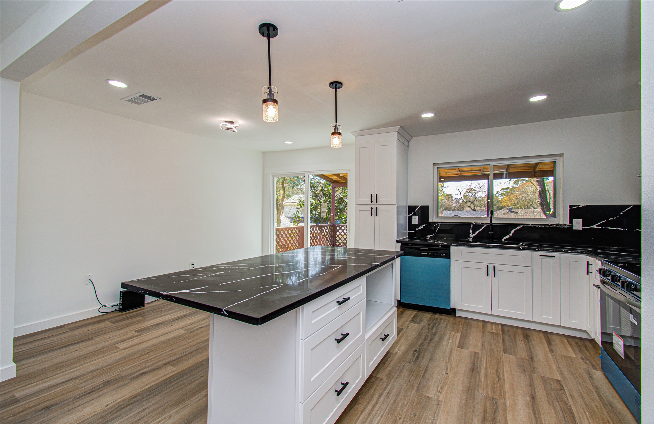 23319 Whispering Willow Drive Spring, TX 77373 - Photo 12 of 41 a kitchen with a stove a sink a kitchen island with wooden floor and windows