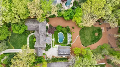 an aerial view of a house with swimming pool and large trees