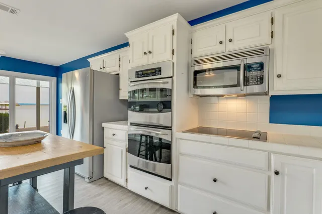 a kitchen with stainless steel appliances white cabinets and wooden floors